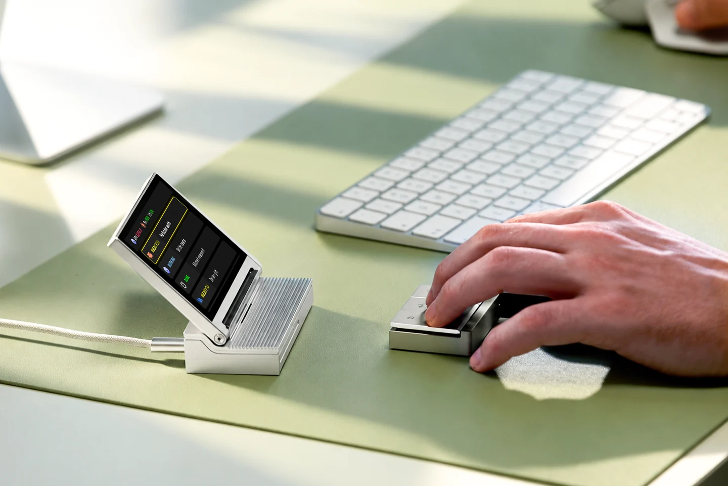 The agent display on the left and detached controller under a hand on the right of a green desk